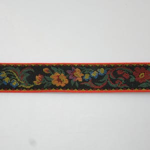 May include: Black ribbon trim with a floral pattern in red, orange, yellow, green, and blue. The trim has a red border.