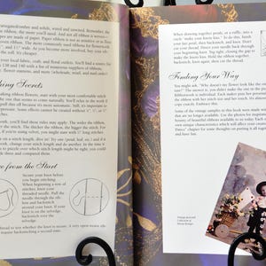 Peut inclure: Livre ouvert avec une couverture &agrave; motif floral color&eacute;. Les pages pr&eacute;sentent des instructions pour la broderie au ruban avec du texte sur "Secrets de couture" et "Trouver votre chemin". Une petite photo d'un enfant dans un jardin se trouve sur la page de droite.