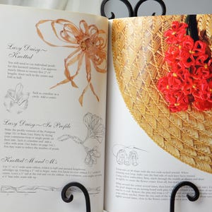 Peut inclure: Un livre avec des instructions sur la fa&ccedil;on de faire un chapeau de paille avec un motif de marguerite rouge. Le livre comprend des instructions pour "Lazy Daisy Knotted" et "Lazy Daisy In Profile".
