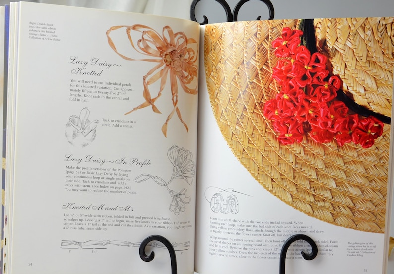 Peut inclure: Un livre avec des instructions sur la fa&ccedil;on de faire un chapeau de paille avec un motif de marguerite rouge. Le livre comprend des instructions pour "Lazy Daisy Knotted" et "Lazy Daisy In Profile".