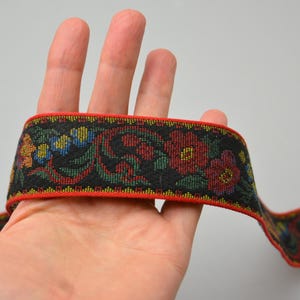 May include: Red, green, and blue floral patterned trim with a black background. The trim has a red border.