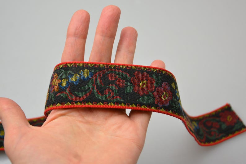 May include: Red, green, and blue floral patterned trim with a black background. The trim has a red border.