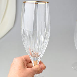 Pu&ograve; includere: Un fl&ucirc;te da champagne trasparente con bordo dorato. Il bicchiere presenta linee incise verticali ed &egrave; tenuto in mano. La base del bicchiere ha un piccolo piede rotondo. Il bicchiere &egrave; elegante e adatto alle occasioni speciali.