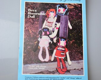 May include: A pattern and instructions for making a reversible doll. The doll is 33 inches (83.8 cm) tall and has two sides, one with a "sleepy" face and one with an "awake" face. The pattern includes instructions for making the doll's clothes.