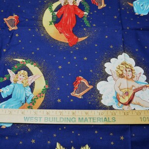 May include: Blue fabric with a celestial design featuring angels, moons, stars, and harps. Angels are depicted in various poses, some playing instruments, others seated on crescent moons. The fabric has a ruler with the text "WEST BUILDING MATERIALS" and "1010 CHESTNUT".