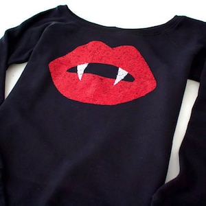 May include: Black long-sleeved shirt with a red glitter vampire mouth graphic.