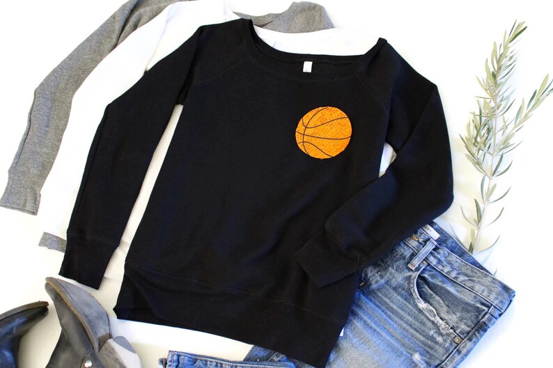 May include: Black sweatshirt with a large orange basketball graphic on the front. The sweatshirt has long sleeves and a relaxed fit.