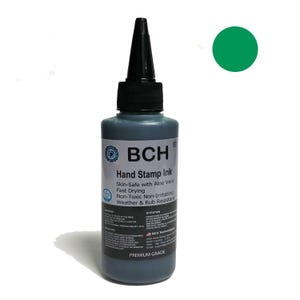 Puede incluir: Una botella de tinta para sellos BCH con tapa negra y etiqueta verde. La etiqueta incluye el texto "Skin-Safe with Aloe Vera" y "Non-Toxic Non-Irritating". Un círculo verde está en la esquina superior derecha.