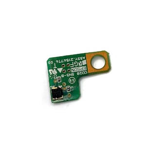 May include: A green circuit board with a small black sensor and a hole in the top right corner. The board has the text "CD28 SNS B-8 EPSON KGF ASSY 2154774 00" printed on it.