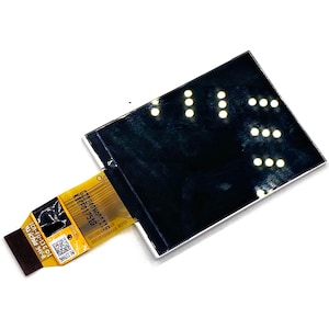 Op de afbeelding: Een close-up van een klein, zwart LCD-scherm met een gele lintkabel eraan bevestigd. Het scherm heeft een witte rand en wordt verlicht door een reeks witte LED's. De lintkabel heeft de tekst "C28240 ΜΟΠΟ119 KICF017519" erop gedrukt.