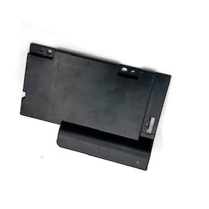 May include: A black plastic laptop component with a rectangular shape and a hinged section. The component has several small holes and a raised edge. The background is white.