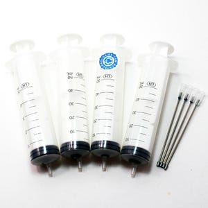 Puede incluir: Cuatro jeringas blancas de 50 ml con émbolos negros y agujas transparentes. Cada jeringa tiene marcas graduadas y el texto "LH" y "ml". Una jeringa tiene un logotipo azul y blanco que dice "BCHTECHNOLOGIES.COM".