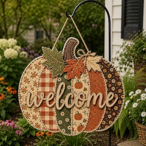 May include: A hanging pumpkin-shaped sign featuring a patchwork design of orange, green, and brown fabrics with floral, gingham, and pumpkin patterns. The word welcome is written in large, cursive, light-colored script across the center.