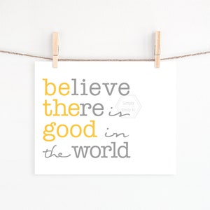May include: A white printable art print with the text "believe there is good in the world" in gray and yellow lettering. The text "Simply Emily H" is in a gray hexagon.