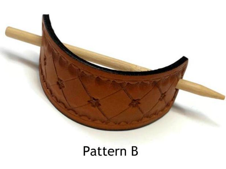 May include: A brown leather hair stick holder with a diamond pattern and a wooden stick. The holder is labeled "Pattern B".
