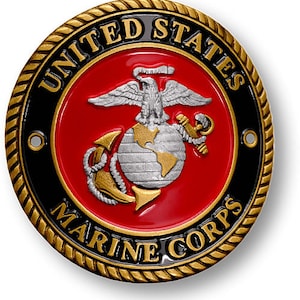 May include: A gold-coloured metal emblem with a black and red centre. The emblem features the words "United States Marine Corps" and a stylised eagle, globe, and anchor.