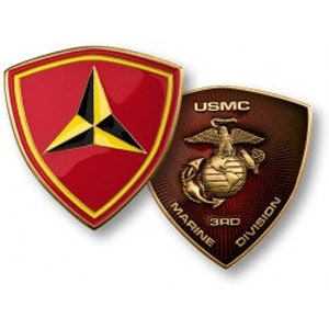 May include: A gold-coloured challenge coin with two sides. The front side features a red shield with a gold border and a yellow triangle inside. The back side features a red shield with a gold eagle, globe, and anchor. The text "USMC MARINE 3RD DIVISION" is written around the shield.