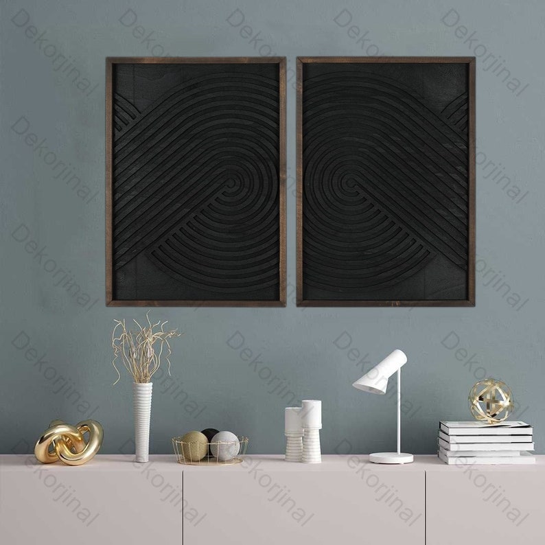 May include: Two black and white abstract geometric wall art pieces in wooden frames, displayed on a light pink shelf with decorative objects.
