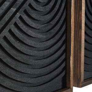 May include: Two black wood wall panels with a geometric pattern of curved lines. The panels are framed in dark wood.