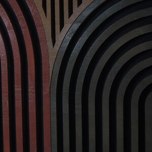Op de afbeelding: Abstracte geometrische wandkunst met een ontwerp van overlappende bogen in tinten bruin, grijs en zwart.
