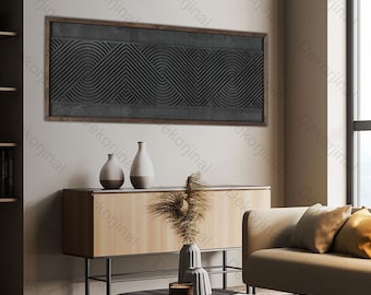 May include: A living room interior design with a black and white geometric wall art, a wooden cabinet with three vases, a coffee table with a book and a candle, and a beige sofa with pillows.