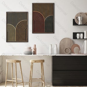 Op de afbeelding: Twee ingelijste abstracte kunstprints met geometrische vormen in tinten van bruin, rood en grijs. De prints hangen aan een witte muur boven een keukenblad met twee houten krukken.