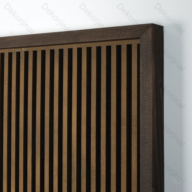 Op de afbeelding: Een bruin houten frame met verticale latten, die een decoratief wandpaneel vormen. De latten zijn gerangschikt in een herhalend patroon van licht- en donkerbruin.