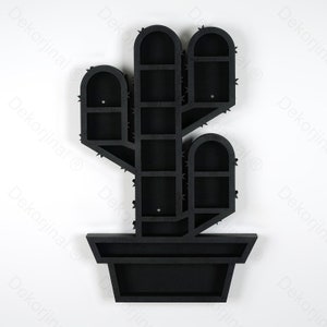 May include: Black wooden cactus-shaped wall shelf with multiple compartments. The shelf is designed to resemble a cactus in a pot, featuring arched compartments and spiky details. A decorative and functional piece for home decor.