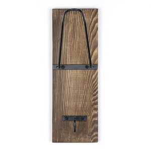 May include: A rustic wooden wall hook with a black metal hook and a black metal bar. The hook is attached to the wall with two screws.