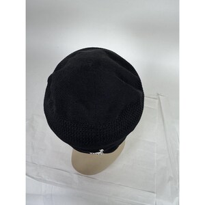 May include: Black knit hat with a mesh design on the sides. The hat has a small white logo on the front. The hat is shown on a mannequin head.