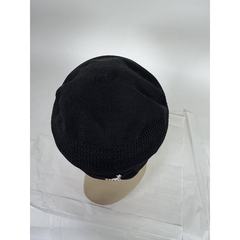 May include: Black knit hat with a mesh design on the sides. The hat has a small white logo on the front. The hat is shown on a mannequin head.