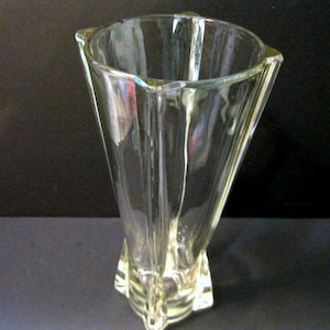 May include: A clear glass vase with a geometric design. The vase has a wide mouth and a narrow base.