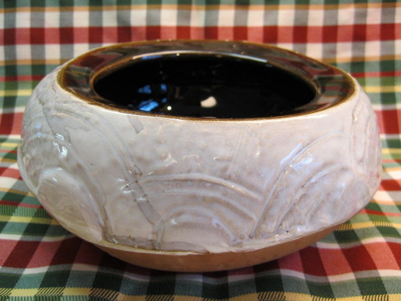 May include: A white ceramic bowl with a brown rim and a textured design. The bowl is empty and has a glossy finish.