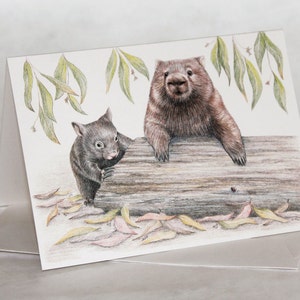 May include: A hand-drawn illustration of two wombats, one adult and one baby, sitting on a log. The adult wombat is brown and has a black nose, while the baby wombat is black. The background is white with green leaves.