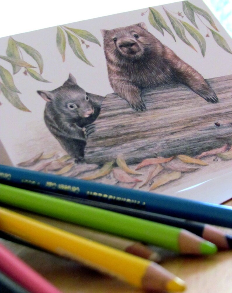 May include: A watercolor illustration of a wombat and a smaller marsupial sitting on a log. The wombat is brown and has a black nose. The smaller marsupial is black and has a white nose. The background is a white paper with green leaves.