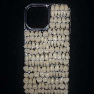 May include: A clear phone case featuring a design of hundreds of white teeth arranged in rows.