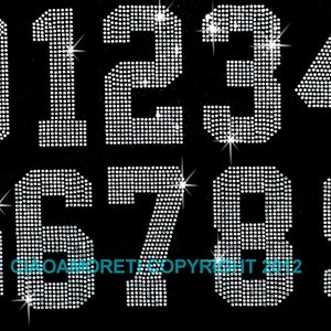 May include: Ten iron-on rhinestone numbers, 0 through 9, in a silver color. Each number is made of small, closely spaced rhinestones.