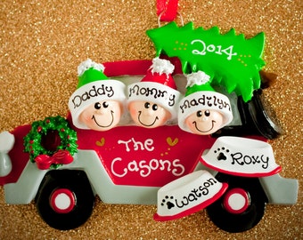 May include: A red and gray truck Christmas ornament featuring three smiling figures in hats labeled Daddy, Mommy, and Madilyn, with a green tree on top marked 2014. The truck side says The Casons, with two pet bowls labeled Roxy and Watson.