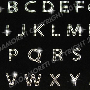 May include: A set of 26 iron-on rhinestone letters in uppercase, A through Z, on a black background. The letters are made of clear rhinestones.