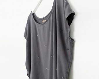 May include: A gray, short-sleeved, loose-fitting t-shirt with a scoop neck and a layered hem. The shirt is decorated with small, iridescent rhinestones.
