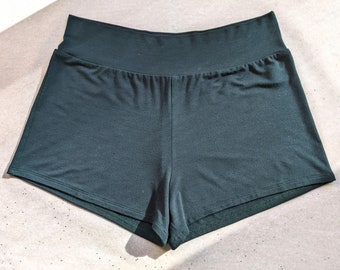 May include: Dark green, high-waisted, short shorts made of a soft, stretchy fabric. The shorts have a wide waistband and a simple, casual design.