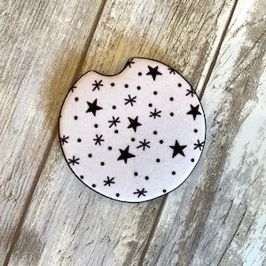 May include: A white round coaster with a black star and dot pattern.