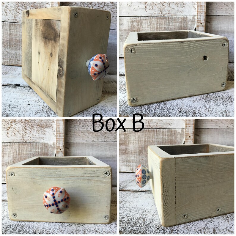 May include: A set of four wooden boxes, each with a rectangular shape and a light beige finish. One box features a decorative knob with blue, orange, and white patterns. The text "Box B" is visible.