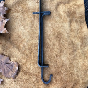 May include: A black metal hook with a double hook design. The hook is made of two pieces of metal that are joined together at the top and bottom. The hook is about 12 inches long.
