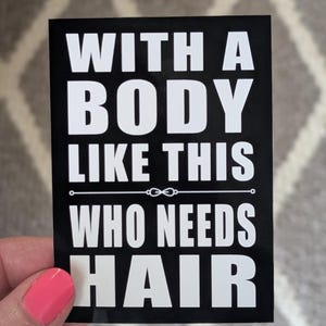 May include: A black rectangular sticker with white text that reads: "WITH A BODY LIKE THIS WHO NEEDS HAIR". The sticker is held by a hand with pink nail polish.
