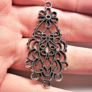 May include: Silver filigree pendant with a flower design at the top and a teardrop shape. The pendant has multiple loops at the bottom.
