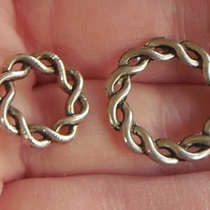 May include: Two silver metal rings with a braided design. The rings are different sizes.