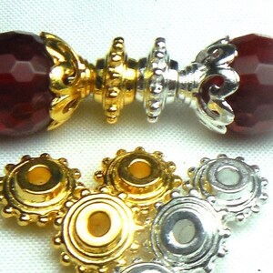 May include: Gold and silver metal bead caps with a decorative, scalloped edge. The bead caps have a small hole in the center for threading.
