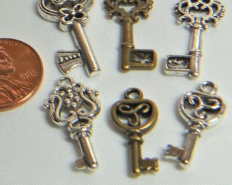 May include: Six ornate key charms, three silver and three bronze, with intricate designs. The keys are about the size of a US penny.