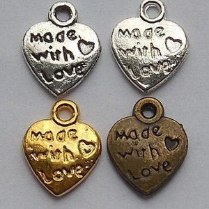 Op de afbeelding: Vier zilveren en gouden hartvormige bedels met de woorden "Made with Love" erop gegraveerd.